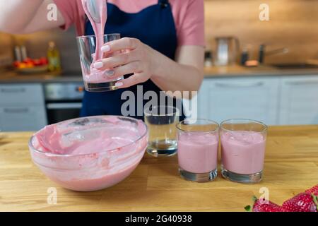 il processo di preparazione di un dessert alla fragola dal latte. Cuoco mette il pudding in tazze e decora Foto Stock