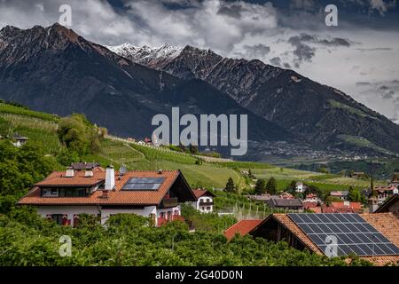 Panorama di batterie solari sul tetto, verdi pendii delle montagne d'Italia, Trentino, Dolomiti, enormi nuvole su una valle, Foto Stock