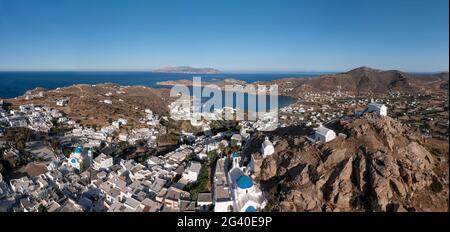 Grecia Cicladi. Isola di iOS, panorama della città di Chora vista aerea drone. Architettura tradizionale delle Cicladi, edifici imbiancati calmo Mar Egeo, cielo blu Foto Stock