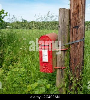 Posto rosso montato George 5th, lettere solo, casella postale in un ambiente rurale con un campo dietro Foto Stock