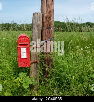 Posto rosso montato George 5th, lettere solo, casella postale in un ambiente rurale con un campo dietro Foto Stock