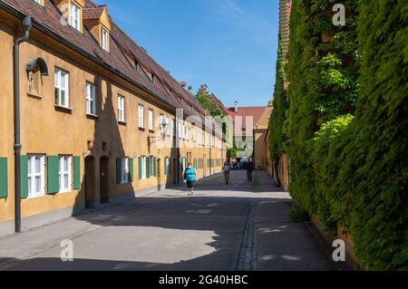 Augusta, Germania. 18 Giugno 2021. I visitatori camminano attraverso il Fuggerei. Il Fuggerei è considerato il più antico insediamento sociale del mondo. Credit: Stefan Puchner/dpa/Alamy Live News Foto Stock