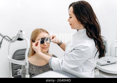 Il medico determina la visione del paziente. Bella donna all'oftalmologo controlla la vista. Prenditi cura della tua salute. Foto Stock