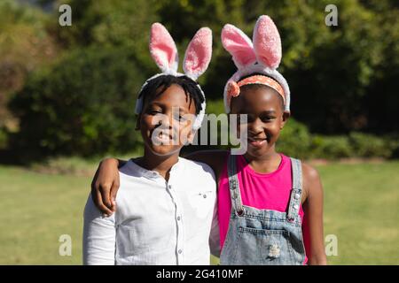 Ritratto di felice fratello afroamericano e sorella abbracciando indossare bunny orecchie all'aperto Foto Stock