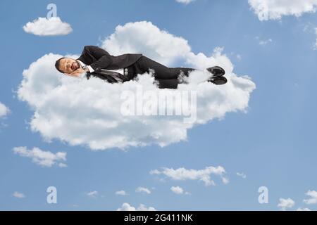 Uomo d'affari che dorme su nuvole e cielo blu Foto Stock