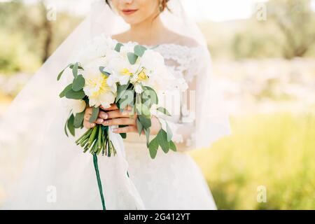 Bella sposa in tenero abito da sposa che tiene in mano bouquet nuziale Foto Stock