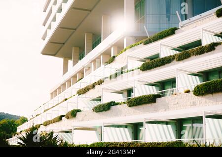 Grande hotel con grandi balconi continui e colonne con vegetazione in una giornata di sole. Foto Stock