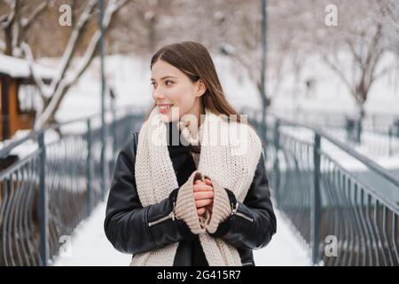 Bella giovane donna in giacca invernale in piedi su un ponte godendo del tempo Foto Stock