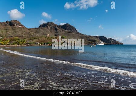 Spiaggia di sabbia nera con nave passeggeri Aranui 5 (Aranui Cruises) sul molo in lontananza, Taiohae, Nuku Hiva, Isole Marquesas, Polinesia francese, Foto Stock