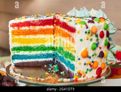 Fetta di torta arcobaleno multicolore. Torta con strati di colori luminosi all'interno Foto Stock