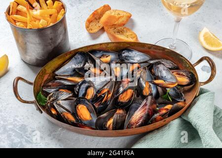 Cena di cozze con vino, patatine fritte e pane tostato Foto Stock