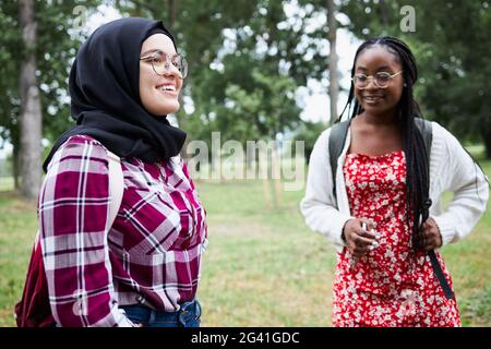 Due amici dell'università che si trovano nel parco universitario e che chiacchierano Foto Stock