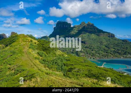 Vista aerea dei veicoli fuoristrada quadrupli su strade sterrate attraverso la lussureggiante vegetazione di montagna, Bora Bora, Isole Leeward, Polinesia francese, Pacifico meridionale Foto Stock