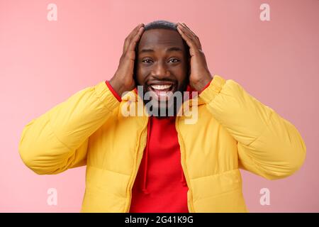 Felice sorpreso soddisfatto giovane afroamericano 25s uomo giovane giacca rosso felpa con cappuccio sorridente divertito, stupito sorridendo awes ricezione Foto Stock