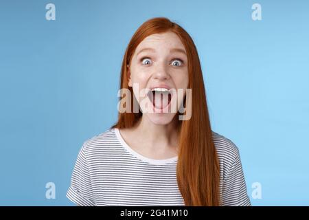 Divertito entusiasta sorpreso bravo-sguardo rosso ragazza occhi larghi sbalorditi goccia mascella gridare stupito sguardo impressionato Foto Stock