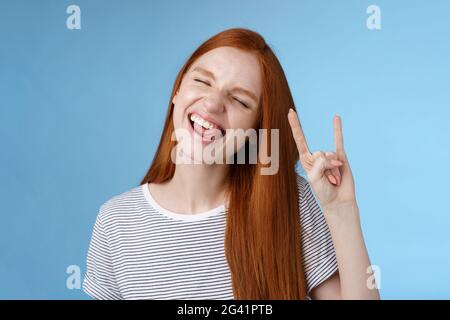 Felice allegro spensierato agghiacciante ragazza adolescente rossa avendo divertimento bastone lingua occhi vicini che ballano gioiosamente mostra rock-n-roll pesante Foto Stock