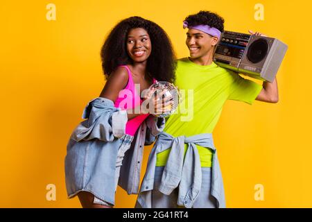 Ritratto di una coppia allegra e allegra che abbraccia divertirsi trasportando il giocatore retrò isolato su sfondo giallo brillante Foto Stock