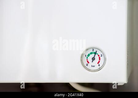 Scala di pressione con una freccia sulla parete di un riscaldatore dell'acqua bianco, primo piano Foto Stock