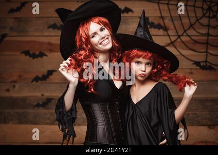 Halloween Concept - bella madre caucasica e sua figlia con lunghi capelli rossi in costumi di strega che celebrano il posin di Halloween Foto Stock