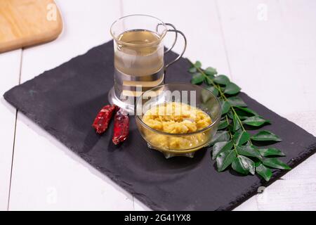 Ingredienti - pasta di aglio allo zenzero, foglie di curry, olio da cucina e peperoncino secco disposti su una base di grafite con fondo testurizzato. Foto Stock