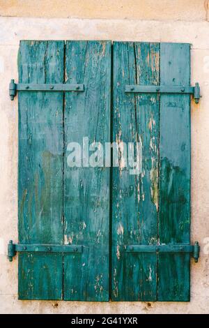 Vecchie persiane chiuse di legno verde con vernice sbucciata. Foto Stock
