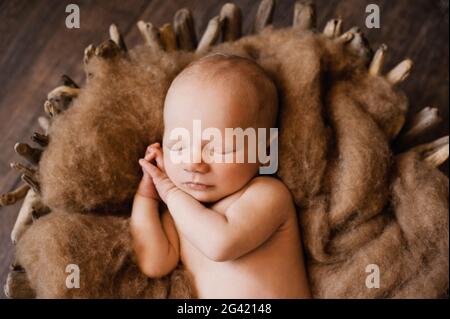 Un bambino che dorme con le mani sotto le guance ad un photoshoot neonato Foto Stock