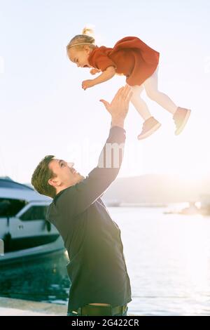 Padre sta gettando in aria la sua figlia di 2 anni al tramonto Foto Stock