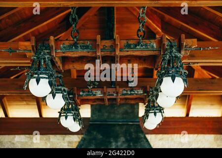 Un enorme lampadario in ferro battuto con palline bianche rotonde. Lampadario a sospensione in metallo in stile cavaliere. Foto Stock