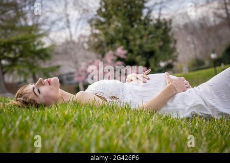 Una meravigliosa donna incinta incandescente posa in un ambiente esterno Foto Stock