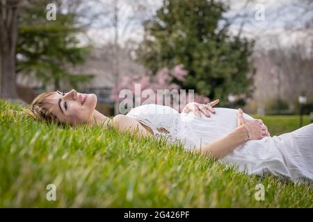 Una meravigliosa donna incinta incandescente posa in un ambiente esterno Foto Stock