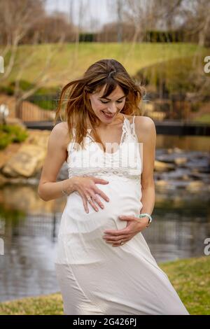 Una meravigliosa donna incinta incandescente posa in un ambiente esterno Foto Stock