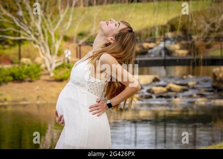 Una meravigliosa donna incinta incandescente posa in un ambiente esterno Foto Stock