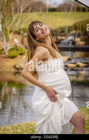 Una meravigliosa donna incinta incandescente posa in un ambiente esterno Foto Stock