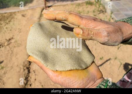 Donna che fa pane piatto indiano o pakistano fatto di miglio perla conosciuto come Bajre ki roti. L'impasto viene appiattito con le mani per formare un cerchio rotondo. Village st Foto Stock