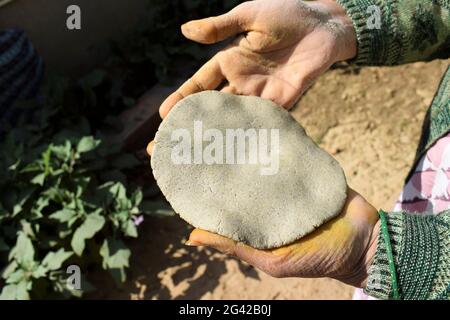 Femmina che fa Bajra o Jowar roti conosciuto come Pearl millet pasta flatbread. Processo di fabbricazione di bajre ki roti in stile villaggio Foto Stock
