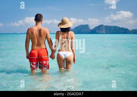 Vista posteriore di una coppia felice innamorata godendo delle calde acque tropicali dell'oceano Foto Stock