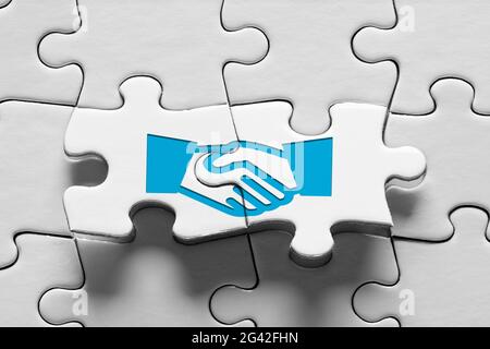 Puzzle con icona di handshake. Accordo commerciale, consenso, alleanza strategica o concetto di partnership. Foto Stock