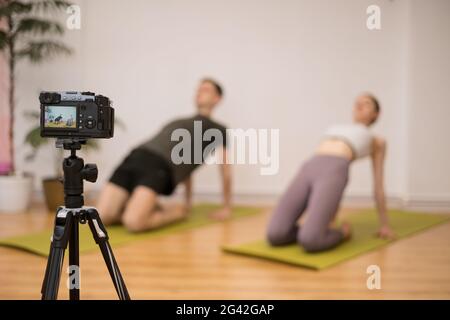Yoga Trainer insegnamento on-line programma di formazione in casa studio dietro fotocamera. Istruttori sportivi che mostrano le pose di yoga, spiegando, dando qualche altro suggerimento. Foto Stock