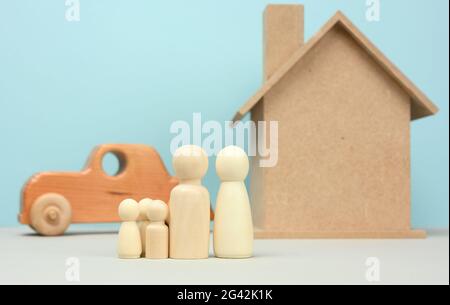 Casa di legno e auto con figure di famiglia in miniatura, ipoteca e concetto di prestito Foto Stock