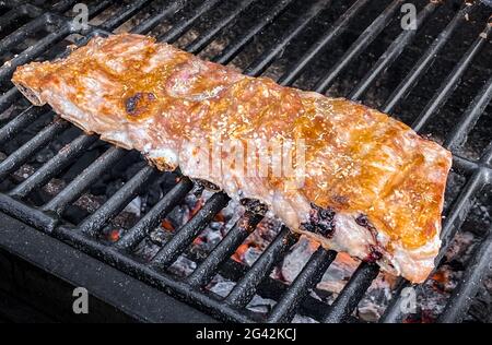 Gustose costolette di maiale su una griglia barbecue. Primo piano di delizioso maiale alla griglia cucinato in barbecue di casa giardino in vacanza. Carne arrosto croccante in Spagna Foto Stock