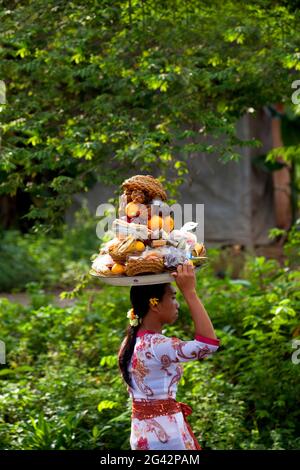 Una giovane donna balinese, con offerte equilibranti sulla testa. Bali, Indonesia. Foto Stock