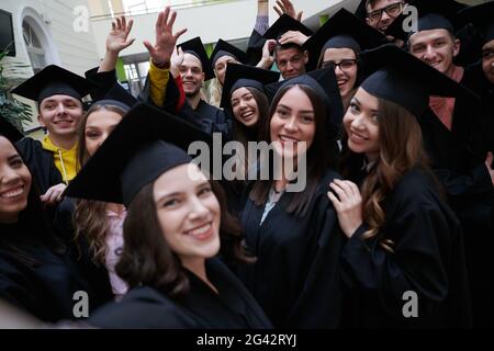 Gruppo di studenti internazionali felici in tavole di Malta e camici di laurea con diplomi di selfie da smartphone Foto Stock