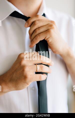 Un uomo si mette e lega un legame mentre si prepara per una cerimonia nuziale, primo piano Foto Stock