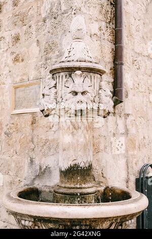 Primo piano piccola fontana all'angolo dell'edificio, in una piazza nella città vecchia di Dubrovnik, Croazia. Una vecchia pietra da bere Foto Stock