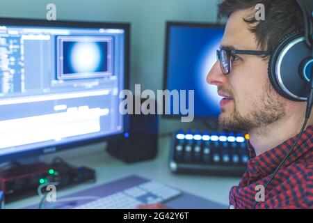 Sala di taglio professionale per l'editing video e la produzione video: Monitor e scrivania di mixaggio audio Foto Stock