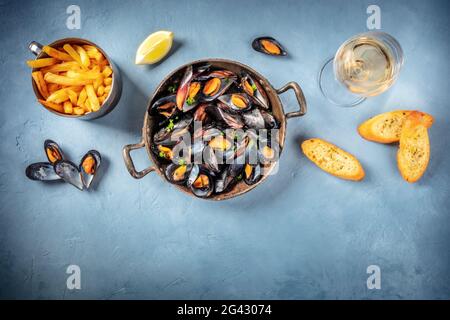 Cozze con vino, patatine fritte, pane tostato e limone Foto Stock