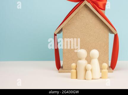 Casa di legno e figure di famiglia in miniatura, ipoteca e concetto di prestito Foto Stock