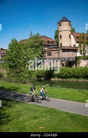 Ciclisti in pista lungo il Tauber con l'ex Corte principesca e Torre Bianca delle mura della città alle sue spalle, Wertheim, Spessart-Mainland, Franco Foto Stock