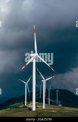 Turbine eoliche elevate contro il cielo di piombo. Foto Stock