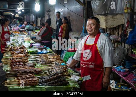 L'uomo vende spiedini di pesce perfettamente grigliati al mercato notturno, Luang Prabang, provincia di Luang Prabang, Laos, Asia Foto Stock